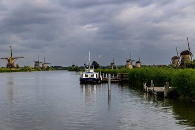 Hollanda 'nın Kinderdijk köyünde günbatımında güzel ahşap yel değirmenleri. Rüzgar değirmenleri esiyor. Güzel Hollanda kanalları suyla doludur. Güzel gün batımı.