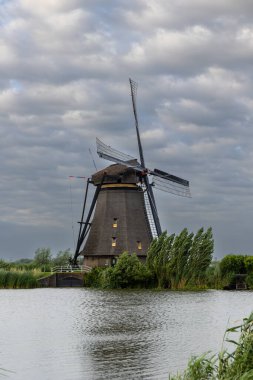 Hollanda 'nın Kinderdijk köyünde günbatımında güzel ahşap yel değirmenleri. Rüzgar değirmenleri esiyor. Güzel Hollanda kanalları suyla doludur. Güzel gün batımı.