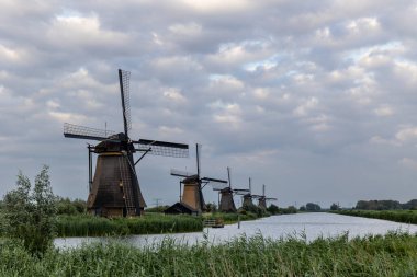 Hollanda 'nın Kinderdijk köyünde günbatımında güzel ahşap yel değirmenleri. Rüzgar değirmenleri esiyor. Güzel Hollanda kanalları suyla doludur. Güzel gün batımı.