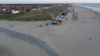 Hollanda 'da. Yazın Katwijk aan Zee sahilinde güzel bir uçuş. İnsanlar deniz kenarında dinleniyor. Turistler için evler. Kuzey Denizi üzerinde güzel bir gün batımı.