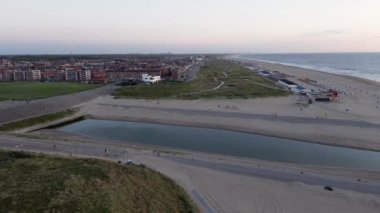 Hollanda 'da. Yazın Katwijk aan Zee sahilinde güzel bir uçuş. İnsanlar deniz kenarında dinleniyor. Turistler için evler. Kuzey Denizi üzerinde güzel bir gün batımı.