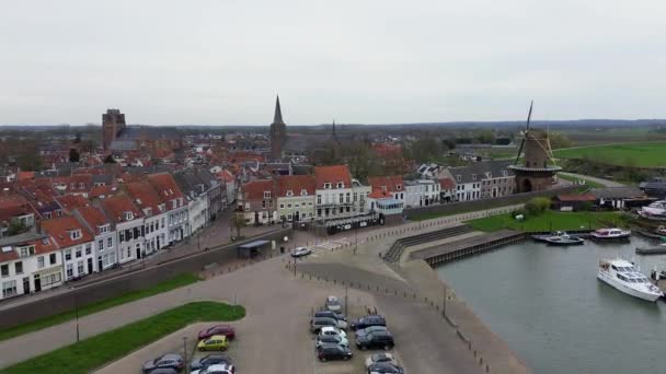 从上方俯瞰美丽的风景 从无人侦察机到橙色的屋顶 布满瓦片的房屋 荷兰城市Wijk Bij Duurstede的全景 许多游艇和小船停泊在海湾里 美丽的风车 — 图库视频影像