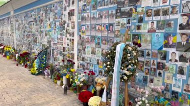 Ukrayna askeri ve polisinin Ukrayna 'ya karşı savaşta öldürülen fotoğraflarıyla dolu bir duvar. Rusya Federasyonu 'nun birçok insanın ölümüne yol açan saldırganlığı. Anıtın yanındaki çiçekler..