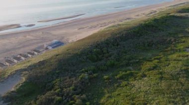 Yazın Katwijk aan Zee sahilinde güzel bir uçuş. İnsanlar deniz kenarında dinleniyor. Turistler için evler. Plaj şemsiyeleri, gezintiler, denizde yüzen insanlar. Hollanda 'da bir plaj. Kuzey Denizi.