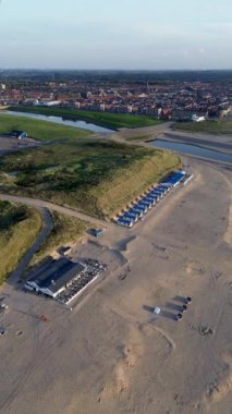 Yazın Katwijk aan Zee sahilinde güzel bir uçuş. İnsanlar deniz kenarında dinleniyor. Turistler için evler. Plaj şemsiyeleri, gezintiler, denizde yüzen insanlar. Hollanda 'da bir plaj. Kuzey Denizi.