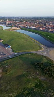 Yazın Katwijk aan Zee sahilinde güzel bir uçuş. İnsanlar deniz kenarında dinleniyor. Turistler için evler. Plaj şemsiyeleri, gezintiler, denizde yüzen insanlar. Araba parkı.