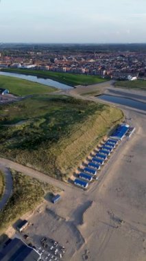 Yazın Katwijk aan Zee sahilinde güzel bir uçuş. İnsanlar deniz kenarında dinleniyor. Turistler için evler. Plaj şemsiyeleri, gezintiler, denizde yüzen insanlar. Hollanda 'da bir plaj. Kuzey Denizi.