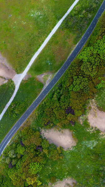 A beautiful bike path shot from above. Flying a quadcopter over a bike path. Green grass and bushes near the beach in the Netherlands. Sand dunes. Beautiful flight in summer over the beach.