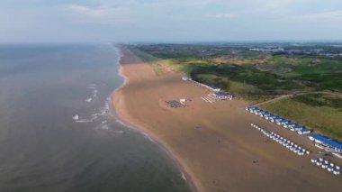 Yazın Katwijk aan Zee sahilinde güzel bir uçuş. İnsanlar deniz kenarında dinleniyor. Turistler için evler. Plaj şemsiyeleri, gezintiler, denizde yüzen insanlar. Hollanda 'da bir plaj. Kuzey Denizi.