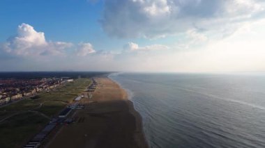 Yazın Katwijk aan Zee sahilinde güzel bir uçuş. İnsanlar deniz kenarında dinleniyor. Turistler için evler. Plaj şemsiyeleri, gezintiler, denizde yüzen insanlar. Hollanda 'da bir plaj. Kuzey Denizi.