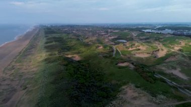 Yazın Katwijk aan Zee sahilinde güzel bir uçuş. İnsanlar deniz kenarında dinleniyor. Turistler için evler. Plaj şemsiyeleri, gezintiler, denizde yüzen insanlar. Hollanda 'da bir plaj. Kuzey Denizi.