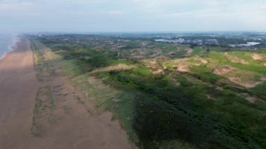 Yazın Katwijk aan Zee sahilinde güzel bir uçuş. İnsanlar deniz kenarında dinleniyor. Turistler için evler. Plaj şemsiyeleri, gezintiler, denizde yüzen insanlar. Hollanda 'da bir plaj. Kuzey Denizi.