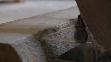 Bıçkıhanede, bir testere kahverengi ahşap keser. Ağaç kabuğu ve eski paslı testere. Yakın plan. Kereste fabrikasında çalış. Tahta ve odun parçalarından toz uçar.