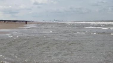 Yazın Katwijk aan Zee sahilinin güzel manzarası. İnsanlar deniz kenarında dinleniyor. Turistler için evler. Plaj şemsiyeleri, gezintiler, denizde yüzen insanlar. Hollanda 'da bir plaj. Kuzey Denizi.