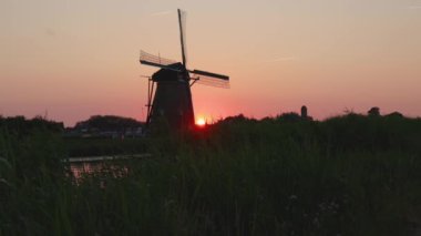 Hollanda 'nın Kinderdijk köyünde günbatımında güzel ahşap yel değirmenleri. Rüzgar değirmenleri esiyor. Güzel Hollanda kanalları suyla doludur. Güzel gün batımı.