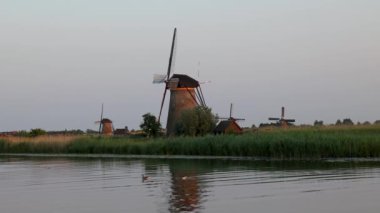 Hollanda 'nın Kinderdijk köyünde günbatımında güzel ahşap yel değirmenleri. Rüzgar değirmenleri esiyor. Güzel Hollanda kanalları suyla doludur. Güzel gün batımı.
