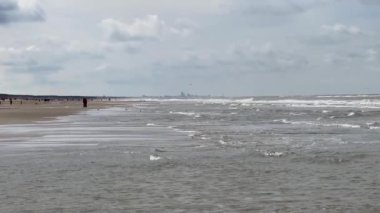 Yazın Katwijk aan Zee sahilinin güzel manzarası. İnsanlar deniz kenarında dinleniyor. Turistler için evler. Plaj şemsiyeleri, gezintiler, denizde yüzen insanlar. Hollanda 'da bir plaj. Kuzey Denizi.