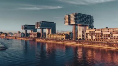 Vinç şeklinde alışılmadık binaları olan modern şehir manzarası. Mavnalar ve gemiler malları Köln 'deki Ren Nehri boyunca taşıyor. Parfüm seti. Sanayi merkezi. Güzel bir akşam zamanı..