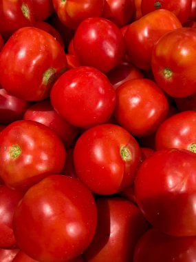 Görüntüde bol miktarda canlı kırmızı domates sergilenen cömert bir görüntü beliriyor. Bu domateslerin çeşitli boyutları ve şekilleri resim gibi bir görüntü yaratıyor..