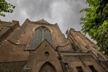 Dramatik bulutlu gökyüzünün altında görkemli bir Gotik kilise. Karmaşık tuğla, yüksek pencereler ve saat kulesi tarihi mimarisini ve zamansız ihtişamını yansıtıyor..
