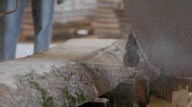 Bıçkıhanede, bir testere kahverengi ahşap keser. Ağaç kabuğu ve eski paslı testere. Yakın plan. Kereste fabrikasında çalış. Tahta ve odun parçalarından toz uçar.