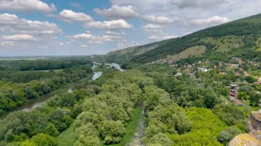 Bereketli yeşil ormanlarla ve açık mavi gökyüzünün altında güneşli bir günde doğanın huzurunu yakalayan bulutlarla çevrili sakin bir nehir manzarası..