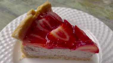 Videoda parlak kırmızı jöle kaplamalı bozulmuş bir cheesecake var. Kremalı peynirli kek ve canlı, parlak ahududu ya da çilekli jelatin karışımı..