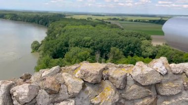 Bereketli yeşil ormanlarla ve açık mavi gökyüzünün altında güneşli bir günde doğanın huzurunu yakalayan bulutlarla çevrili sakin bir nehir manzarası..
