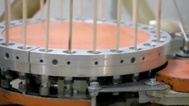 Bir makine ahşap kaplamaları işliyor, onları dairesel bir mekanizmada dikey olarak düzenliyor. Otomatik sistem üretim sırasında hassasiyeti ve tekdüzeliği sağlar..