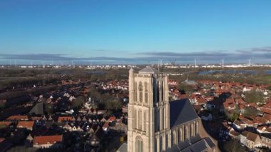 Merkezinde uzun bir Gotik kilisesi olan tarihi bir kasabanın havadan görünüşü. Kırmızı çatılı evler, dar sokaklar ve uzak sanayi silueti eski ve modern mimarinin bir karışımını oluşturuyor..