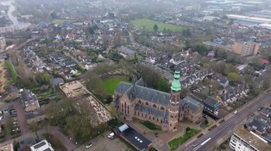 Yeşil kulesi olan tarihi bir kilisenin yer aldığı bir Avrupa kasabasının havadan görünüşü. Etrafında büyüleyici evler, ağaçlarla çevrili sokaklar ve huzurlu, iyi organize edilmiş bir mahalle düzeni var..