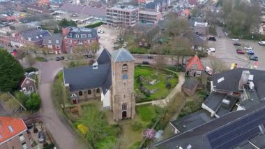 Yeşil kulesi olan tarihi bir kilisenin yer aldığı bir Avrupa kasabasının havadan görünüşü. Etrafında büyüleyici evler, ağaçlarla çevrili sokaklar ve huzurlu, iyi organize edilmiş bir mahalle düzeni var..