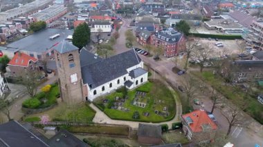 Yeşil kulesi olan tarihi bir kilisenin yer aldığı bir Avrupa kasabasının havadan görünüşü. Etrafında büyüleyici evler, ağaçlarla çevrili sokaklar ve huzurlu, iyi organize edilmiş bir mahalle düzeni var..