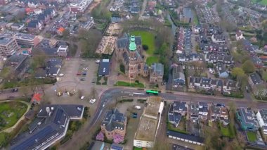 Yeşil kulesi olan tarihi bir kilisenin yer aldığı bir Avrupa kasabasının havadan görünüşü. Etrafında büyüleyici evler, ağaçlarla çevrili sokaklar ve huzurlu, iyi organize edilmiş bir mahalle düzeni var..