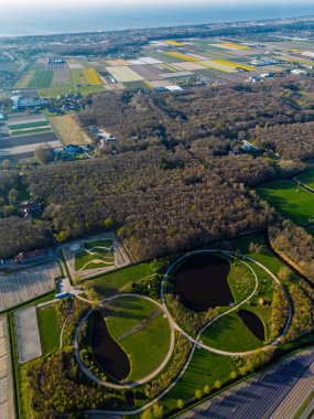 Dairesel yolları ve göletleri olan, renkli tarım arazileriyle çevrili ve sık ormanlarla çevrili eşsiz bir park manzarası. Doğa ve geometrinin çarpıcı bir karışımı.