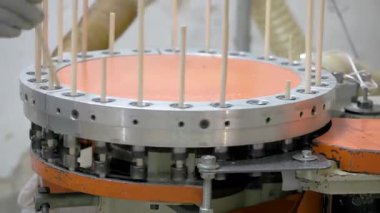 Bir makine ahşap kaplamaları işliyor, onları dairesel bir mekanizmada dikey olarak düzenliyor. Otomatik sistem üretim sırasında hassasiyeti ve tekdüzeliği sağlar..