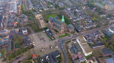 Yeşil kulesi olan tarihi bir kilisenin yer aldığı bir Avrupa kasabasının havadan görünüşü. Etrafında büyüleyici evler, ağaçlarla çevrili sokaklar ve huzurlu, iyi organize edilmiş bir mahalle düzeni var..