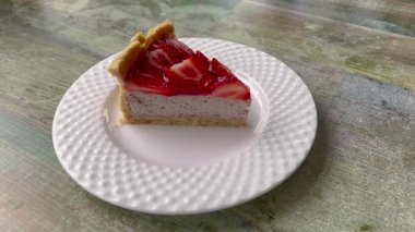 Videoda parlak kırmızı jöle kaplamalı bozulmuş bir cheesecake var. Kremalı peynirli kek ve canlı, parlak ahududu ya da çilekli jelatin karışımı..