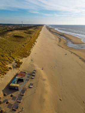 Kıyı boyunca uzanan, berrak mavi gökyüzü ve sakin denizle çevrili, sakin, sakin, doğal bir atmosfer yaratan kumsal manzarası..