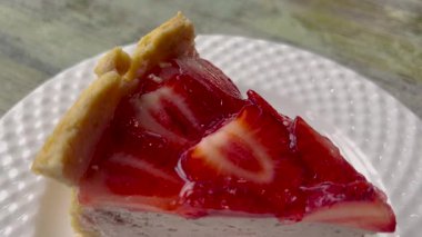 Videoda parlak kırmızı jöle kaplamalı bozulmuş bir cheesecake var. Kremalı peynirli kek ve canlı, parlak ahududu ya da çilekli jelatin karışımı..