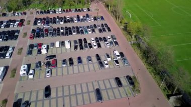 Birçok futbol sahası, bir pist ve saha stadyumu, tenis kortu ve park alanı olan, yemyeşil orman ve renkli lale tarlalarıyla çevrili bir spor kompleksinin havadan görüntüsü..