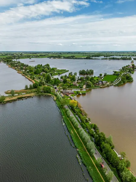 Dar yarımadaları, yeşil tarlaları ve Hollanda kırsalında bulutlu bir gökyüzünün altında sakin sularla çevrili evleri olan manzaralı göl manzaralı bir köy..