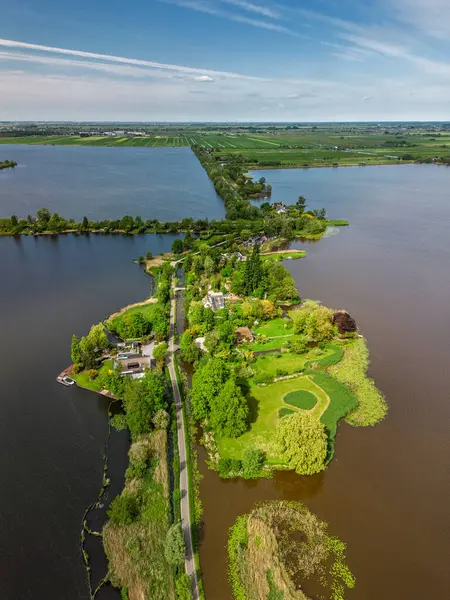 Dar yarımadaları, yeşil tarlaları ve Hollanda kırsalında bulutlu bir gökyüzünün altında sakin sularla çevrili evleri olan manzaralı göl manzaralı bir köy..