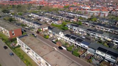 Ev sıraları, çatılarda güneş panelleri, dar sokaklar boyunca park etmiş arabalar ve güneşli bir günde yakalanan küçük bahçelerin bulunduğu yerleşim yerlerinin hava manzarası..