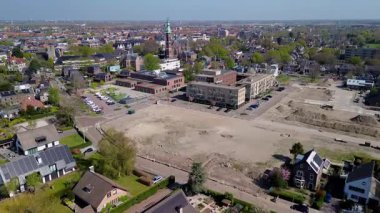 Merkezinde konut evleri, yeşil ağaçlar ve açık mavi bir bahar gününde açık mavi gökyüzü ile çevrili önemli bir kilisenin bulunduğu bir Hollanda kasabasının havadan görünüşü. Huzurlu ve büyüleyici bir atmosfer.