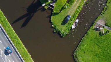 Geleneksel bir yel değirmeni olan, kanal, yeşil tarlalar ve açık mavi gökyüzü altında hareket eden arabaların olduğu bir yol. Renkli bir çiçek tarlasının yukarıdan aşağıya havadan görünüşü.