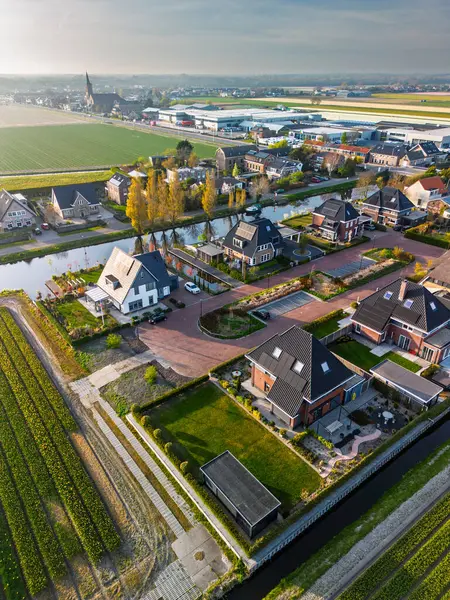Çağdaş evleri ve dar kanallar boyunca bahçeleri olan yeşil tarlalar ve tarım arazileriyle çevrili, uzakta bir kilise ve lale seraları olan büyüleyici bir Hollanda köyü..
