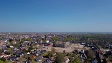 Merkezinde konut evleri, yeşil ağaçlar ve açık mavi bir bahar gününde açık mavi gökyüzü ile çevrili önemli bir kilisenin bulunduğu bir Hollanda kasabasının havadan görünüşü. Huzurlu ve büyüleyici bir atmosfer.