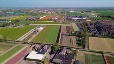 Bir insansız hava aracı temiz tarlaları, konutları, yeşil çimenleri ve güneş panelleri olan binaları olan kırsal bir alanda uçarak huzurlu bir kırsal alan gösteriyor..