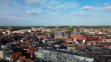 Merkezinde konut evleri, yeşil ağaçlar ve açık mavi bir bahar gününde açık mavi gökyüzü ile çevrili önemli bir kilisenin bulunduğu bir Hollanda kasabasının havadan görünüşü. Huzurlu ve büyüleyici bir atmosfer.